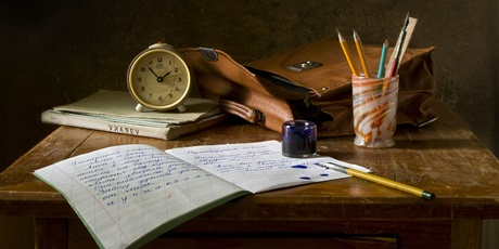 Powiększ grafikę: biurko, na którym leżą torba, zeszyty, zegarek i kredki